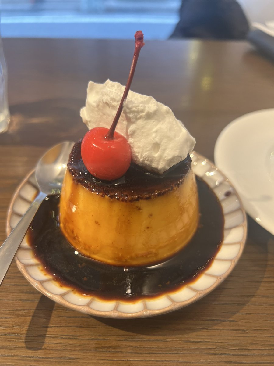 A close-up of the firm custard pudding with dark caramel and a cherry