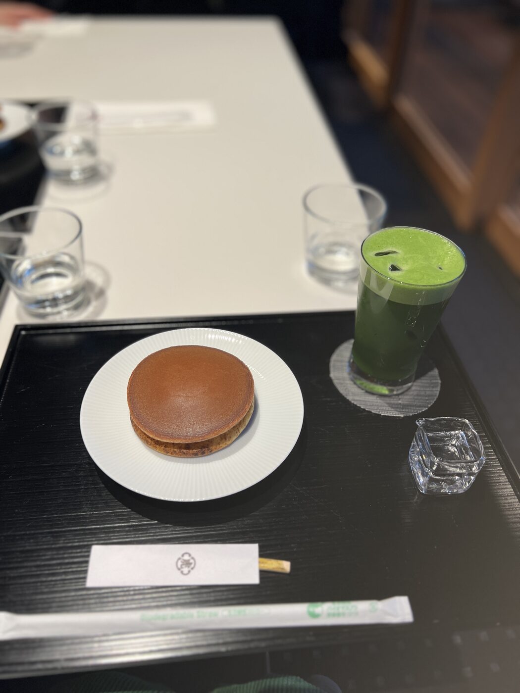 A warm yowa no tsuki dorayaki on a white plate beside a glass of matcha at TORAYA GINZA