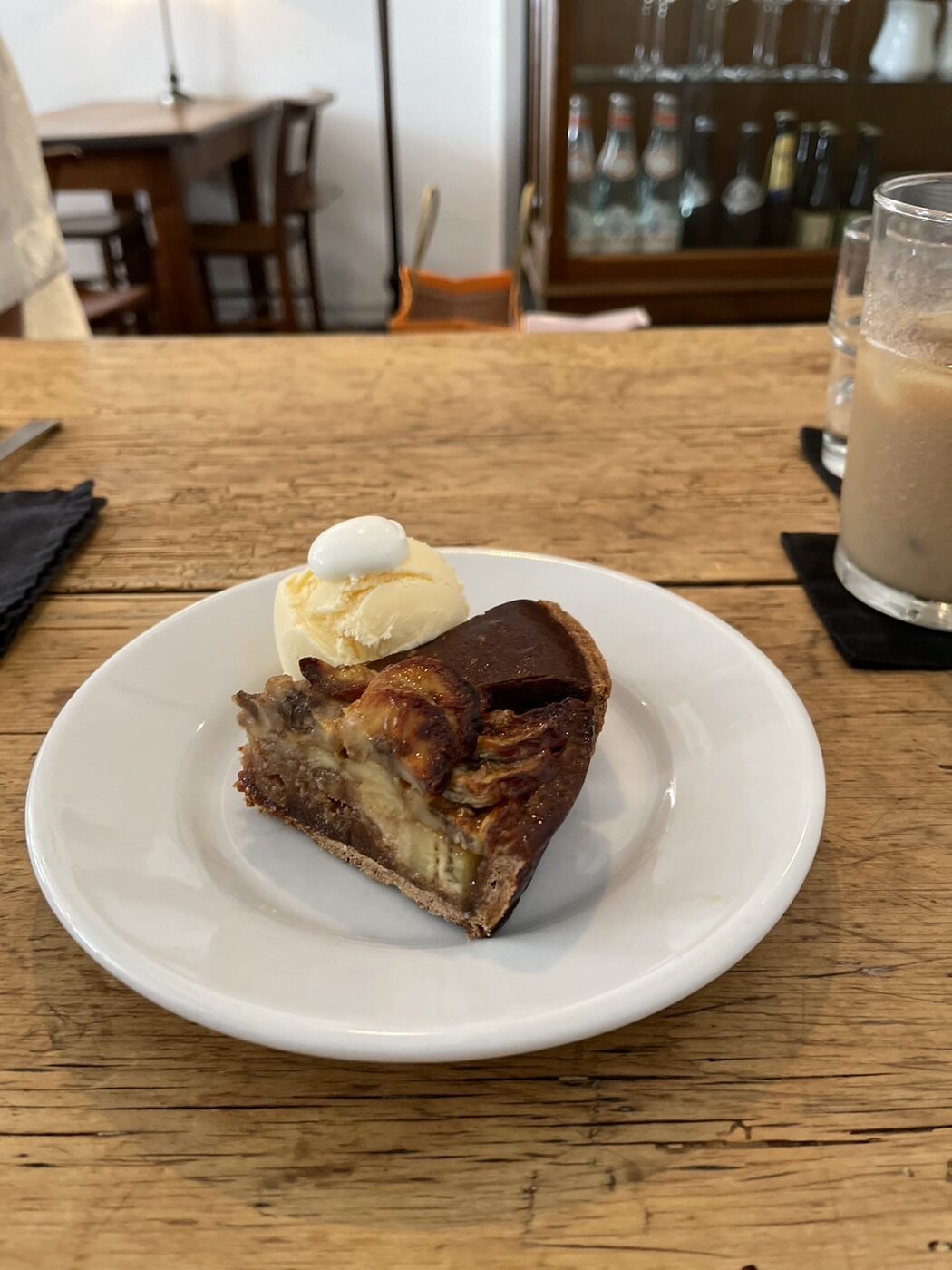 A slice of tart with a scoop of vanilla ice cream on a white plate at Cafe de Lento